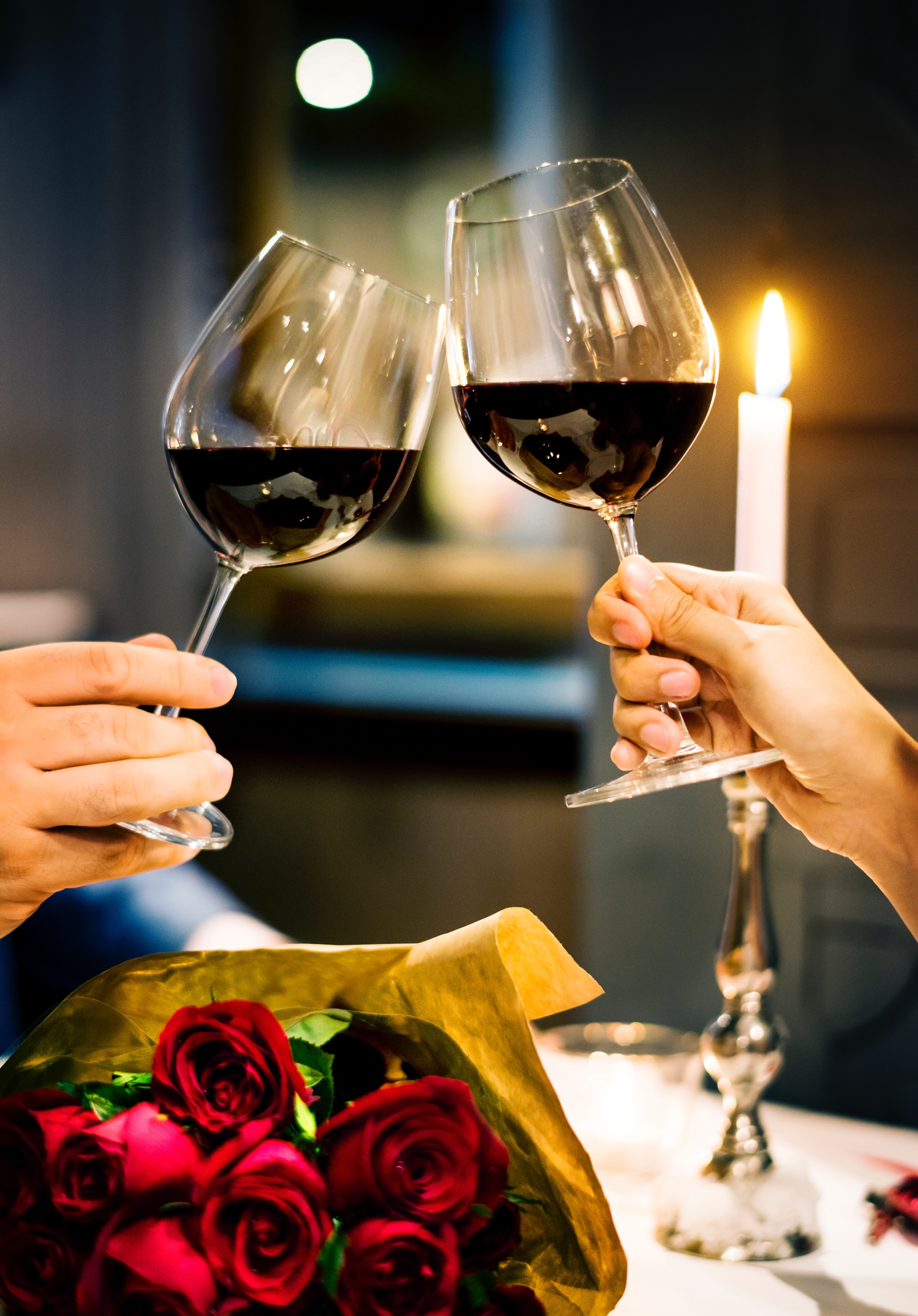 alt="two wine glasses clinking at candlelit dinner"